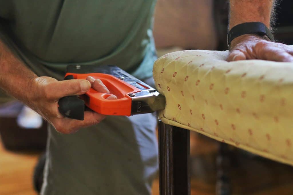 A man uses a cordless staple gun on upholstery