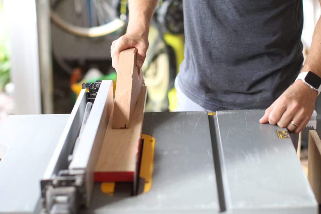 A man feeds a 2x4 through a powerful table saw