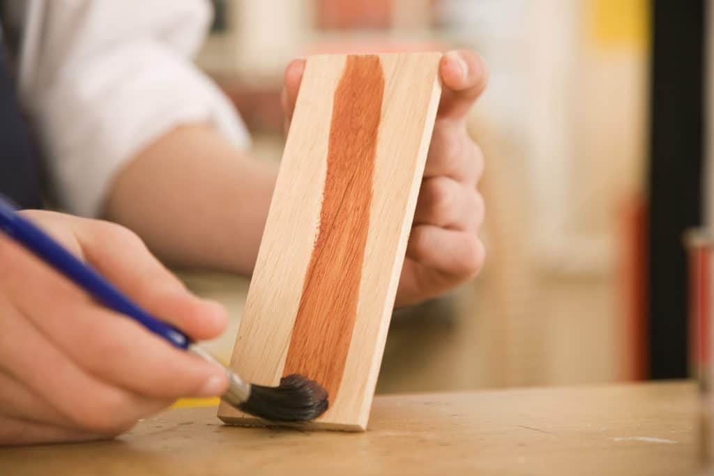 Hands staining wood with polyurethane