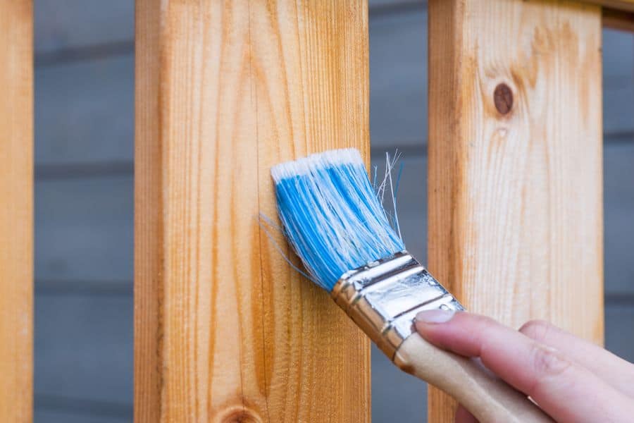 Hand applying shellac on fence