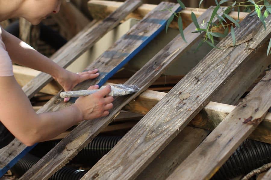 Woman applying wood stain on wood pallets