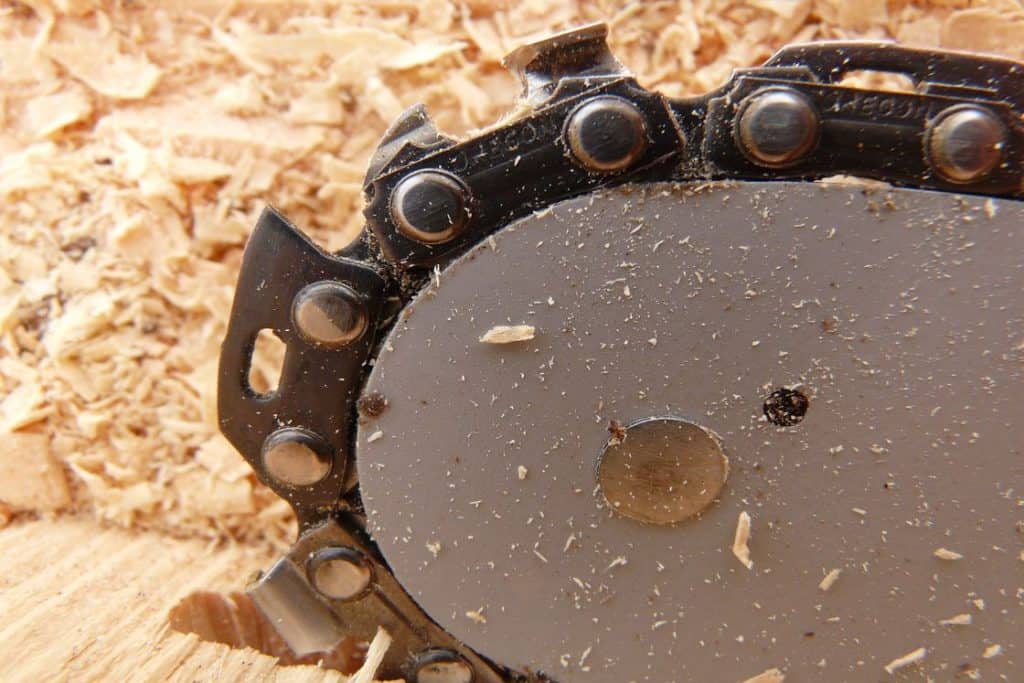 Close up of a chainsaw chain with sawdust in it