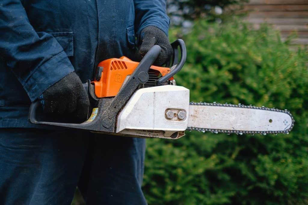 Person wearing gloves while holding a chainsaw