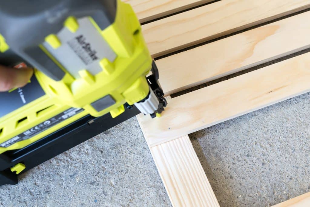 A person used a nailer with green and black coating for a wood project